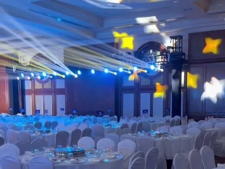 Banquet hall prepared with round tables, covered chairs and event lighting