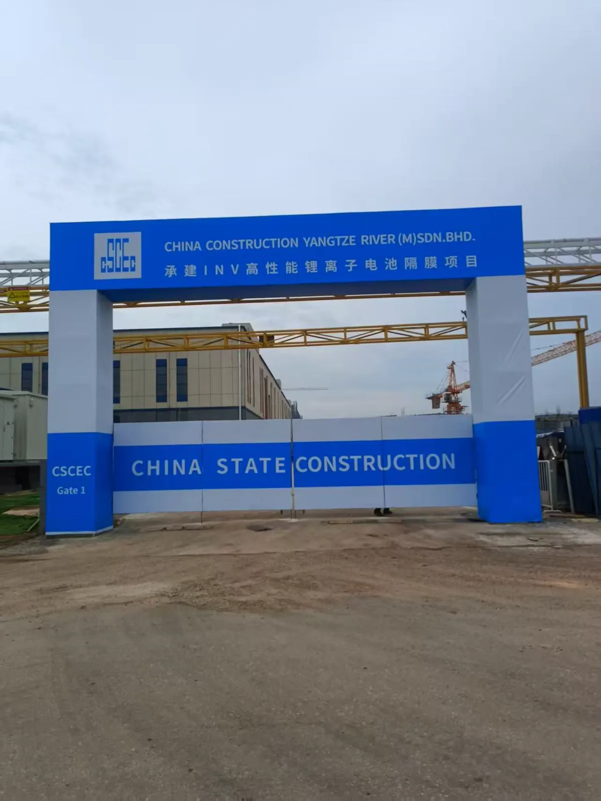 Large blue construction-site entry sign spanning an access road