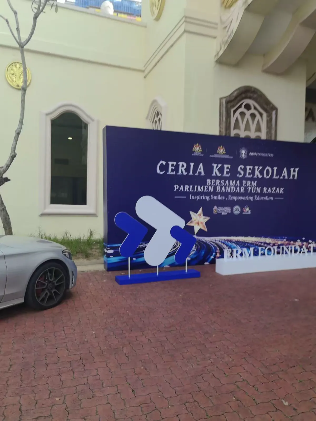Blue freestanding school event backdrop installed at an outdoor arrival area
