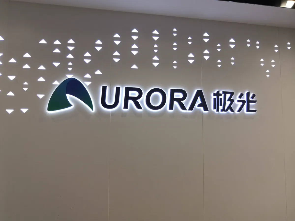 Illuminated Aurora logo installed on a clean office reception wall