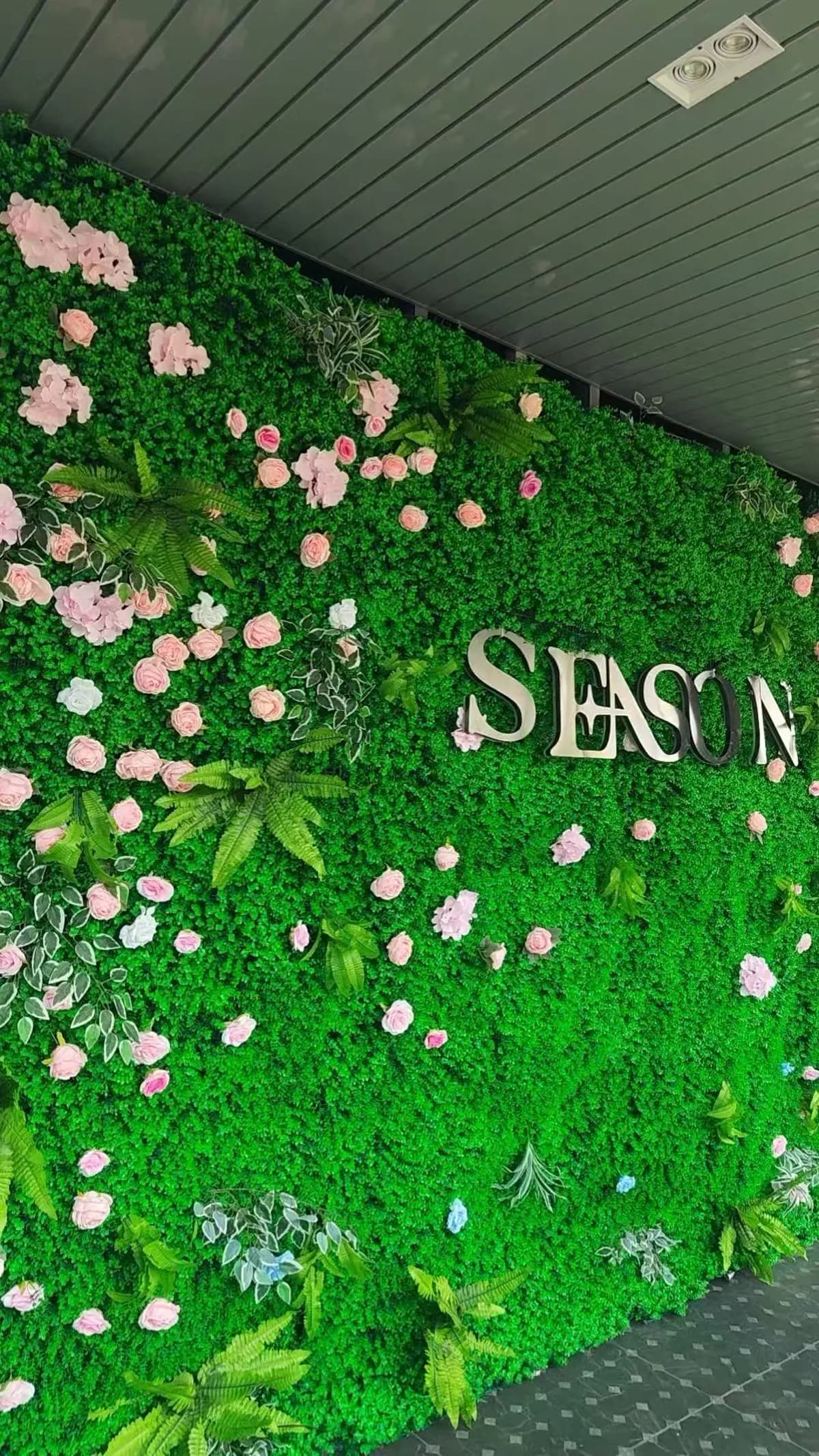 Dimensional SEASON lettering mounted on a decorative green flower wall