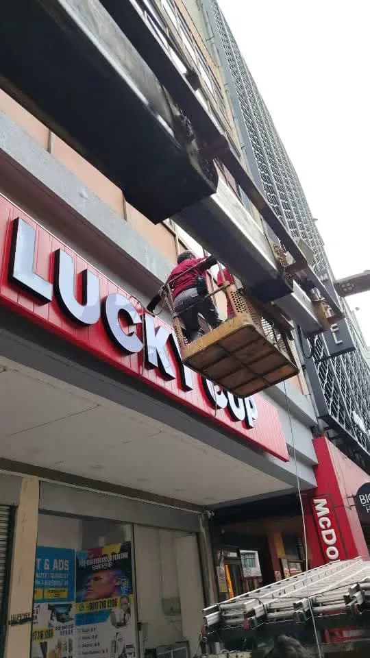 Installer working from a raised platform on illuminated storefront lettering